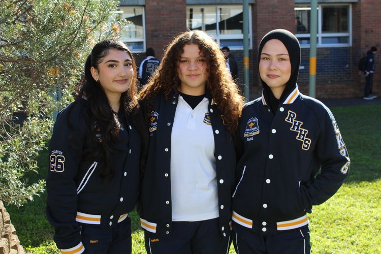 3 students standing together smiling in RHHS senior jackets.