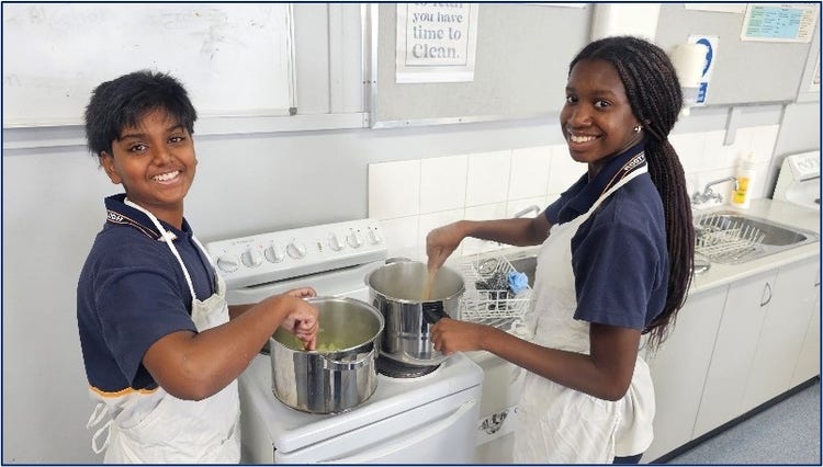 Students stirring a pot on a stove in a school kitchen classroom
